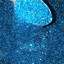 a spoon is scooping blue glitter into a pile of blue glitter .