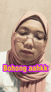 a woman wearing glasses and a pink hijab says bohong