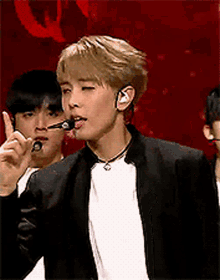 a man wearing a black jacket and a white shirt is holding a microphone in his mouth .