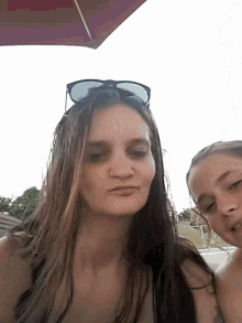 two girls are posing for a picture and one has sunglasses on