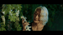 a woman with blonde hair is holding flowers in her hands