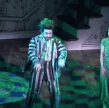 a man in a striped suit is dancing in a dark room