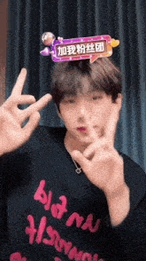 a man wearing a black shirt that says bloom on it is making a peace sign