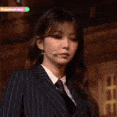 a woman in a suit and tie is standing in front of a microphone and making a funny face .