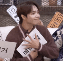 a man in a brown sweater is holding a piece of paper with the number 1929 on it