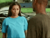 a man and a woman are looking at each other in front of a car .
