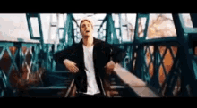 a man is dancing on a bridge with his arms outstretched .