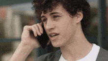 a young man with curly hair is talking on his cell phone