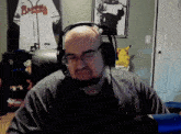 a bald man wearing headphones and glasses is sitting in front of a braves jersey