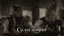 two vikings are sitting at a table and the words ca va saigner are on the screen
