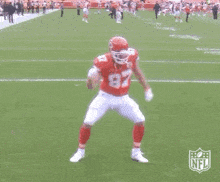 a football player in a red jersey with the number 87 on it is dancing on a field .