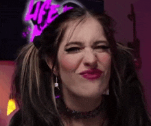 a woman with pigtails is making a funny face in front of a neon sign .