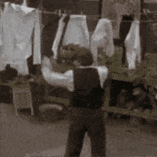a man is standing in front of a clothes line holding a sword .