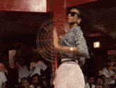 a woman wearing sunglasses is dancing in front of a red exit sign