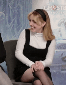 a woman is sitting in front of a ghostbusters frozen poster
