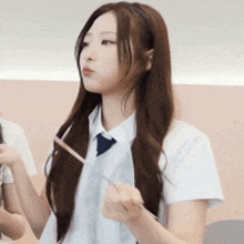 a girl in a white shirt and tie is holding a stick