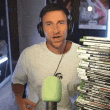 a man wearing headphones holds a stack of call of duty video games