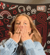 a woman covering her face with her hands in front of a sign that says on air