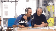 two men wearing headphones are sitting in front of a microphone and the word ciao is on the screen behind them