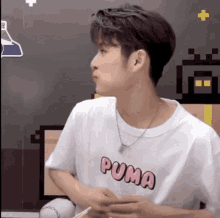 a young man wearing a white puma t-shirt and a necklace is eating noodles .