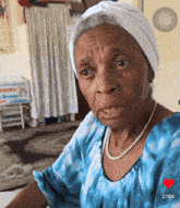 an older woman wearing a blue shirt and pearls has a heart in the corner