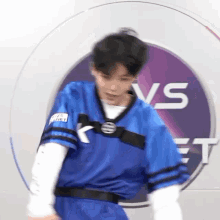 a man in a blue jersey is standing in front of a purple and white circle .