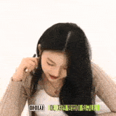 a woman with long black hair is sitting on a bed and talking on a cell phone .