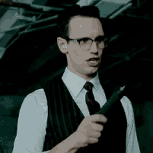 a man wearing glasses , a vest , and a tie is making a funny face .