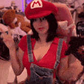 a woman wearing overalls and a mario hat is sitting in a chair
