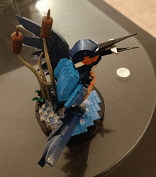 a blue and orange bird made out of lego sits on a table