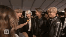 a group of young men are standing next to each other and talking to a woman .