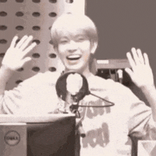 a young man is waving his hands in front of a microphone in a black and white photo .