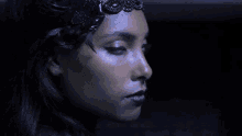 a close up of a woman 's face with a black crown on her head