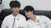 two young men are sitting next to each other on a couch and one of them is wearing a white shirt that says talker