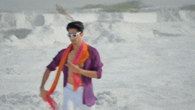 a man in a purple shirt and white shorts is standing on the beach