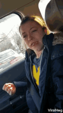 a woman in a car wearing a michigan sweatshirt