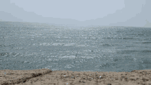 a large body of water with waves crashing against a sandy shore