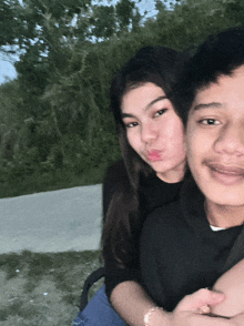 a boy and a girl are posing for a picture and the girl is blowing a kiss