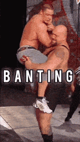 a wrestler is carrying another wrestler in his arms with the word banting written above them