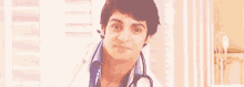 a young man wearing a white coat and a stethoscope is smiling .