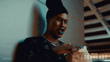 a man with blue nails is holding a bag that says ironheart on it