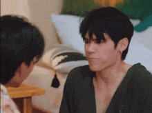 a man in a green shirt is talking to another man in a bedroom