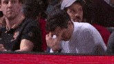 a man covering his face with his hand while wearing a shirt that says ' fc barcelona ' on it