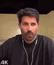 a man with a beard wearing headphones and a black shirt is making a funny face .