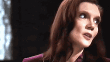 a close up of a woman 's face with a purple shirt on .