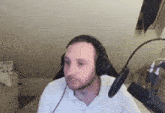 a man wearing headphones and a microphone is sitting in front of a wall .