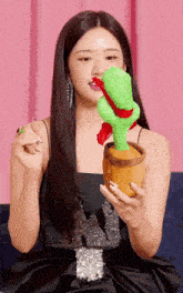 a woman in a black dress is holding a stuffed cactus in her hand