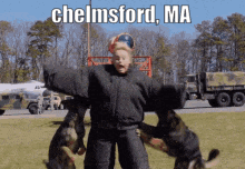 a man in a black jacket is surrounded by two dogs and says chelmsford ma