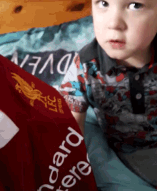 a young boy wearing a red shirt that says standard chartered on it