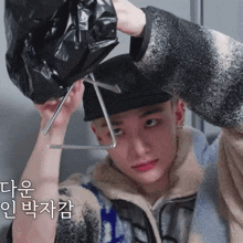 a man wearing a black hat is holding a black bag on his head